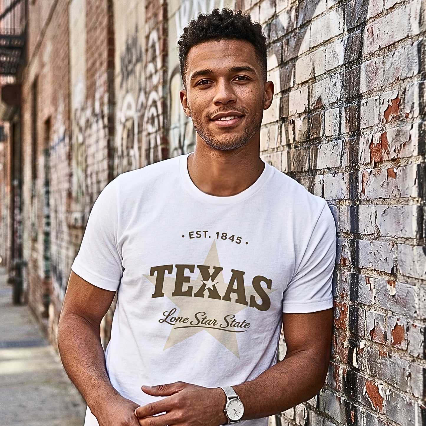 Man wearing a white t-shirt with 'Texas' text standing against a brick wall.