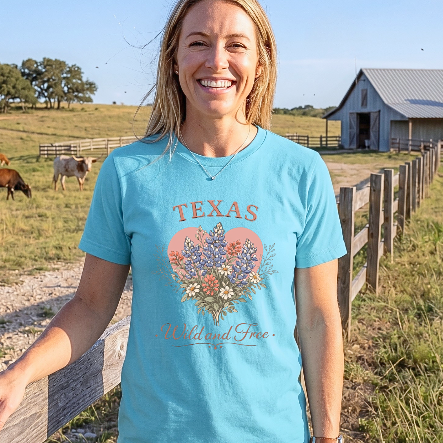 Woman wearing a blue 'Texas Wild and Free' t-shirt standing in a field with cows and a barn.