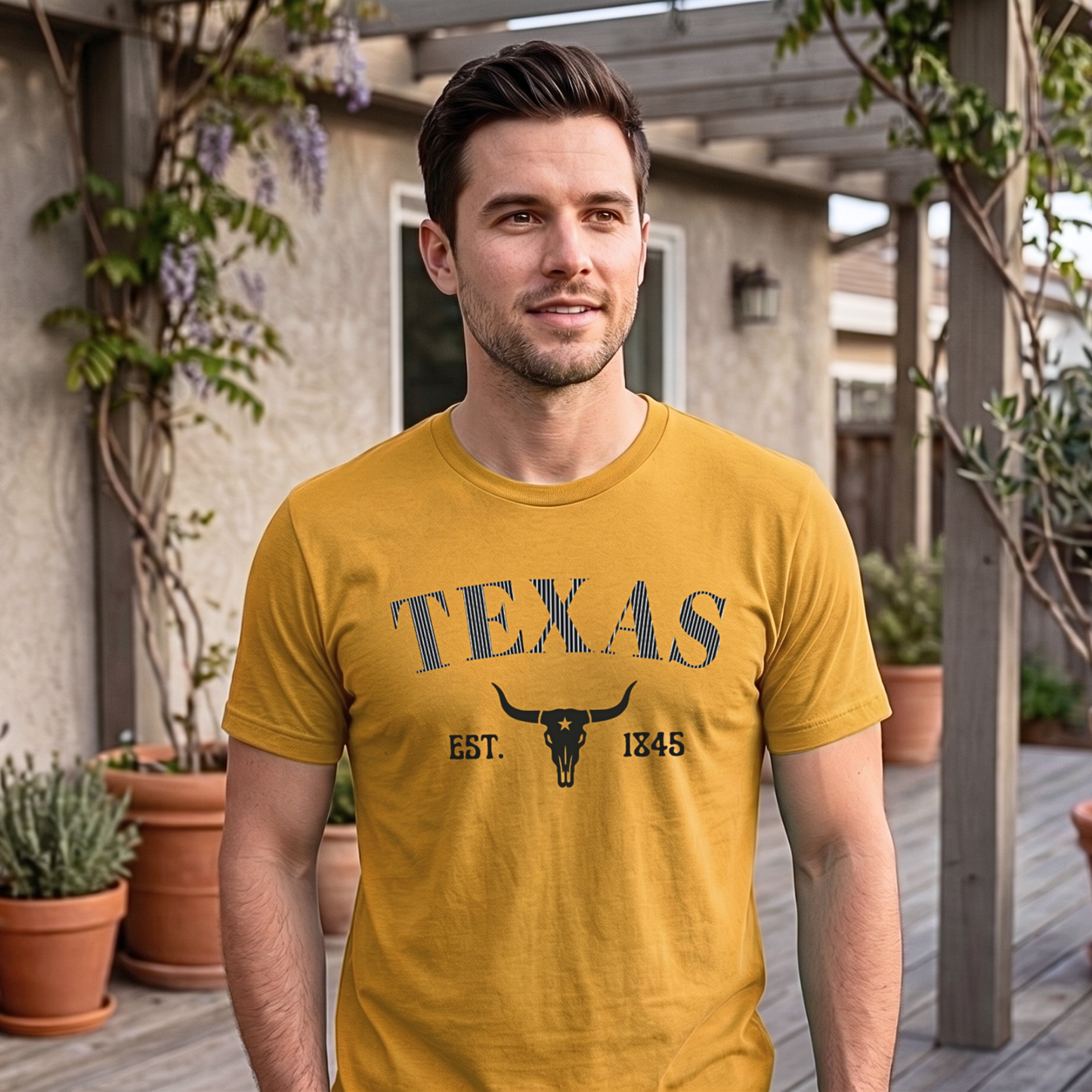 Man wearing a mustard yellow 'TEXAS' t-shirt outdoors with plants and a building in the background