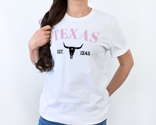 Person wearing a white t-shirt with 'TEXAS EST. 1845' design on a plain background