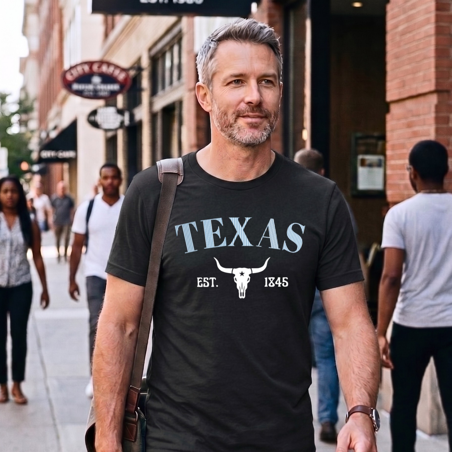 Man wearing a black 'TEXAS' t-shirt with a longhorn skull graphic on a city street.