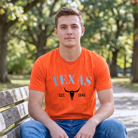 Person wearing an orange 'TEXAS' t-shirt with a longhorn design, sitting on a bench outdoors.