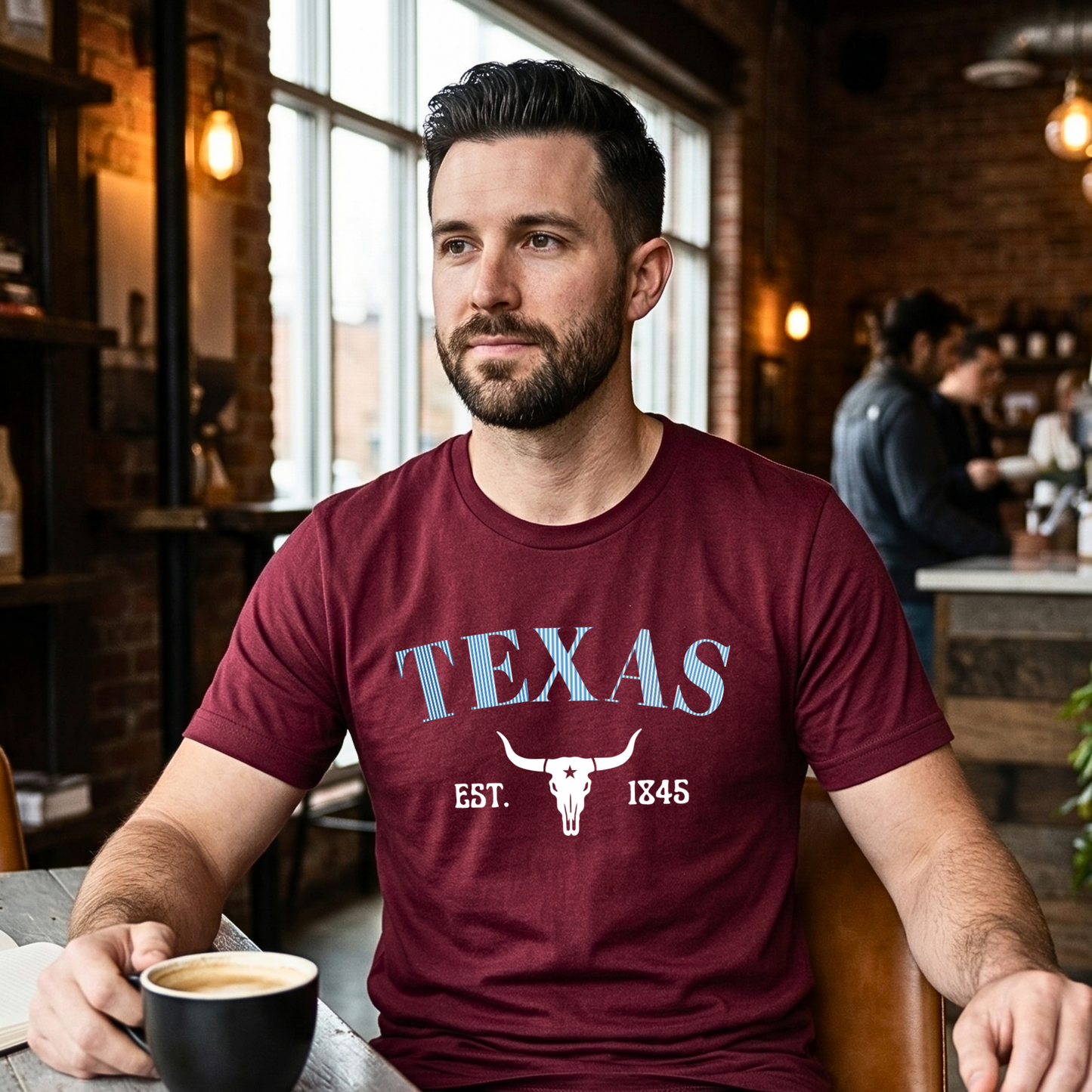 Man wearing a maroon 'Texas' t-shirt in a coffee shop setting