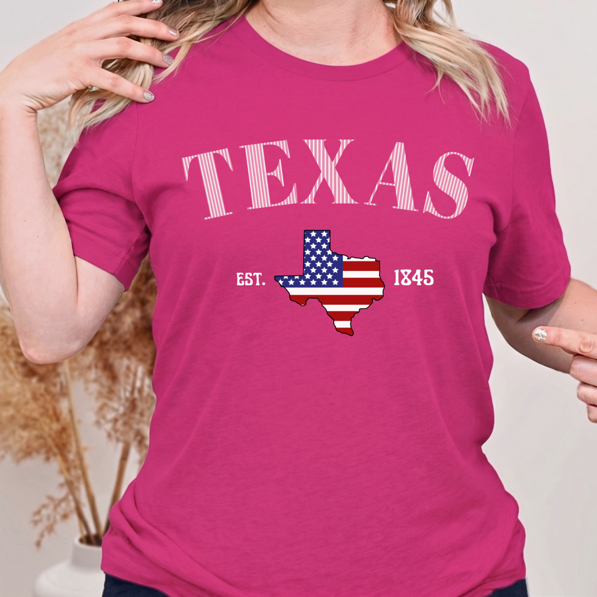 Person wearing a berry bright pink t-shirt with 'TEXAS' and a map of Texas design.