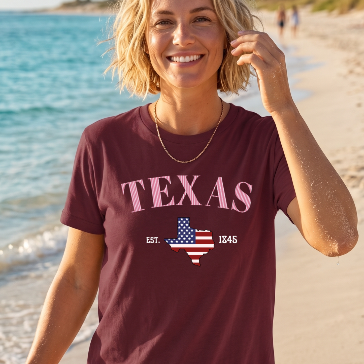Woman wearing a maroon t-shirt with 'TEXAS' and a map of Texas design on a beach.