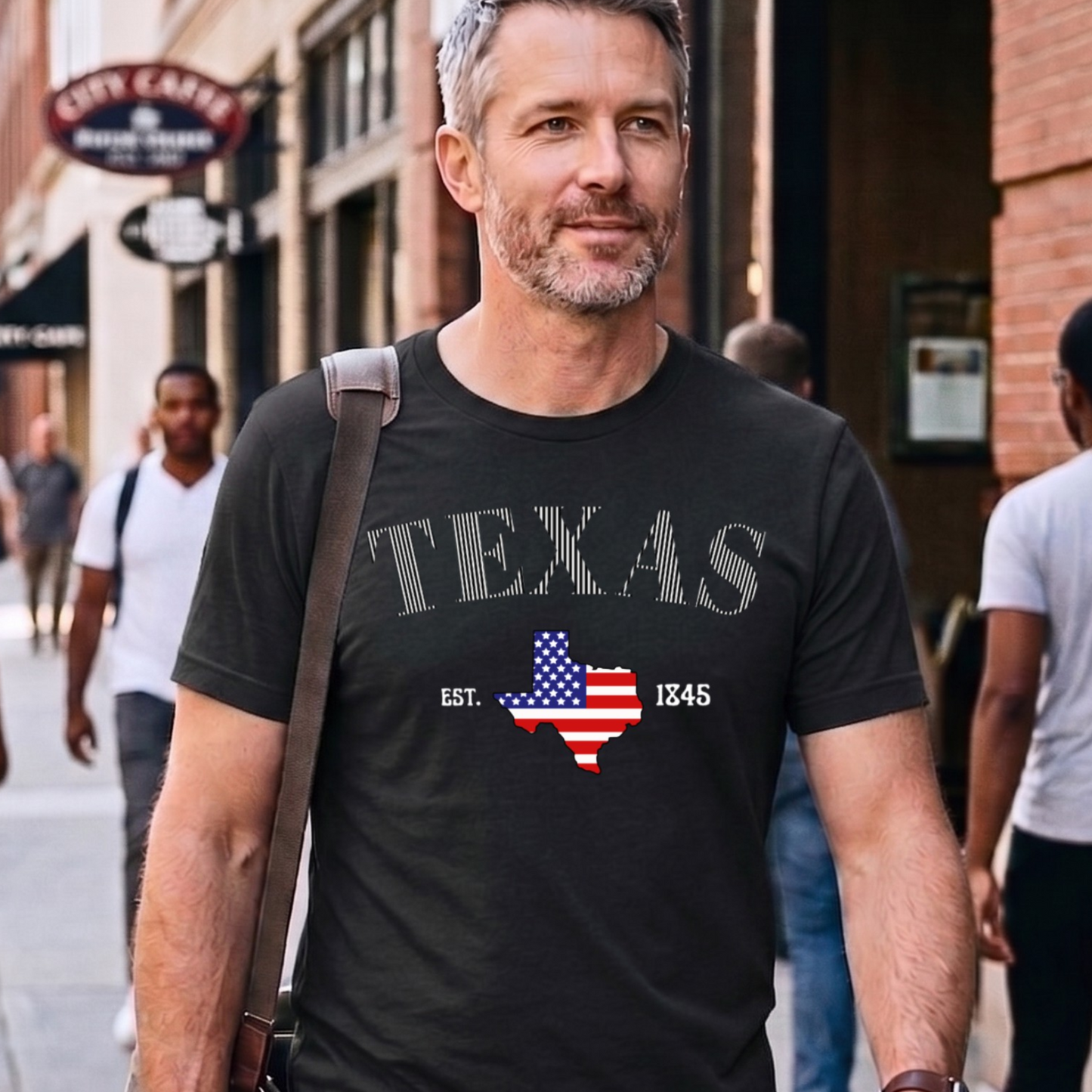Man wearing a black striped 'TEXAS' t-shirt with an American flag design on a city street.
